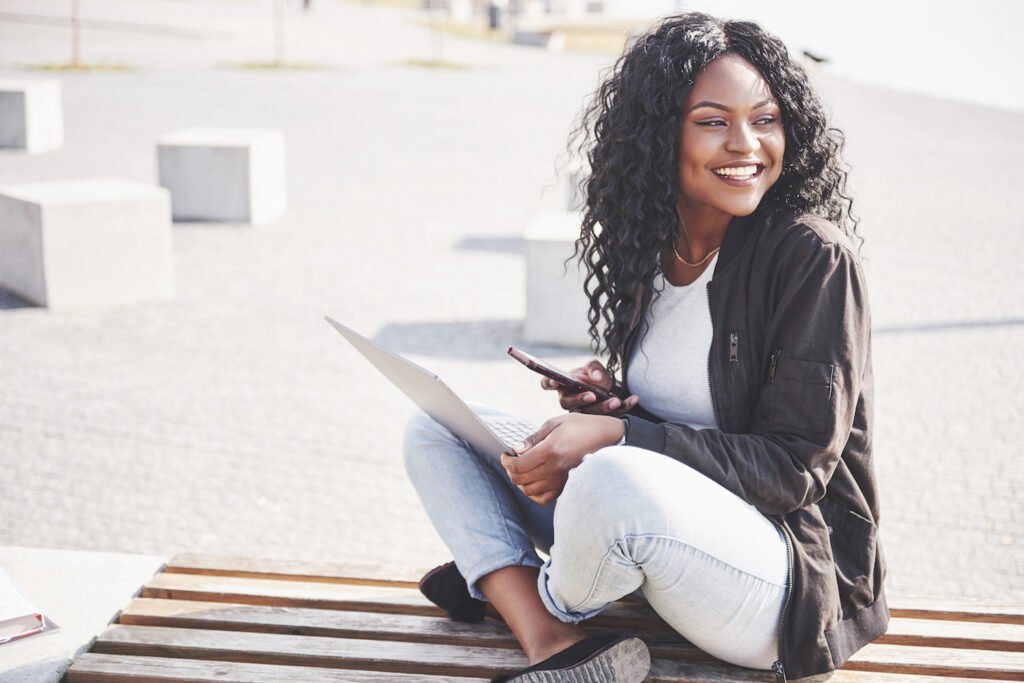 young-woman-on-the-street-working-on-laptop-and-ta-CKBFXL7